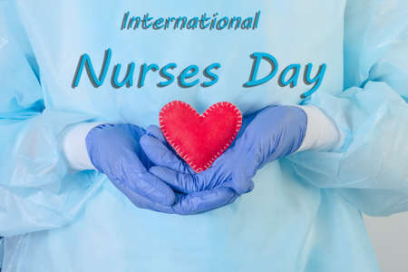 The inscription International Nurses Day against the background of a nurse in blue holding a heart in her hands.の写真素材