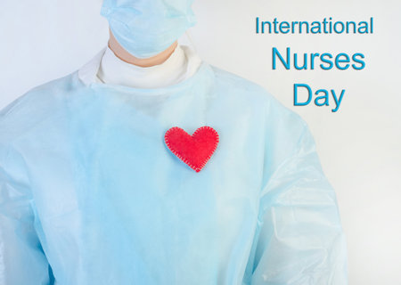 The inscription International Nurses Day on a white background with a nurse in blue with a red heart.の写真素材