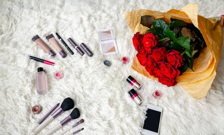 rose flowers in a beautiful bouquet with brushes and decorative cosmetics and a bottle of perfume on a light background, close-upの写真素材