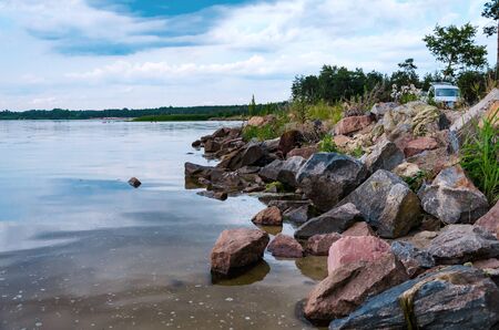 stones by the pond, beautiful summer landscape with trees and blue skyの写真素材