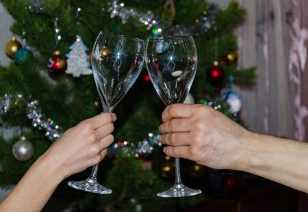 glasses in male and female hands on a background of the Christmas tree, close-upの写真素材