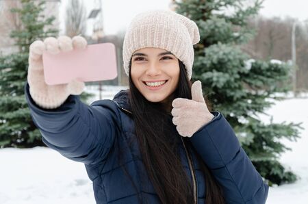 girl with a smartphone calls a friend in the park on a winter day, video call, winter frosty dayの写真素材