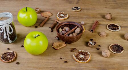 Cinnamon sticks, green apple, nuts, coffee grains and dried fruits on a wooden tableの写真素材
