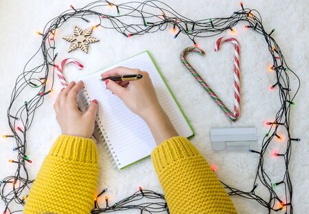 female hands over a notepad, a ballpoint pen and a telephone on the background of the New Year's Eve, close upの写真素材