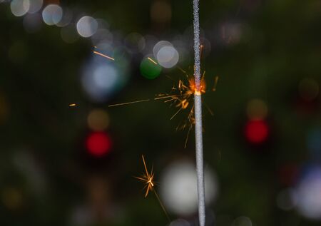 Bengal lights with flying sparks on the background of a Christmas tree, close-upの写真素材