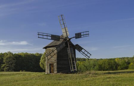 Ancient wooden mill in autumn, against a background of trees and a blue sky, Ukraine