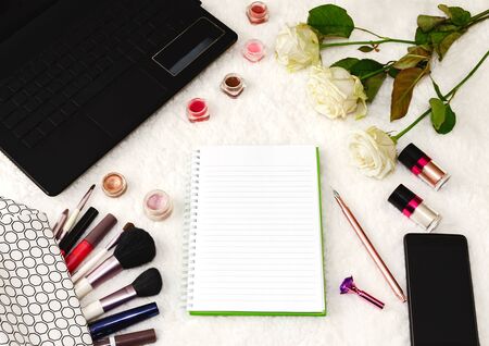 top view of the working area notebook with pen and decorative cosmetics for makeup, soft brushes and flowers, beautiful background closeupの写真素材