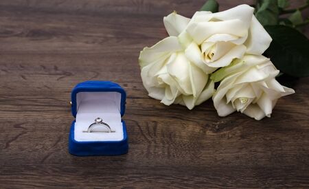 ring in a box, white roses on the table, a gift for the holiday close-up