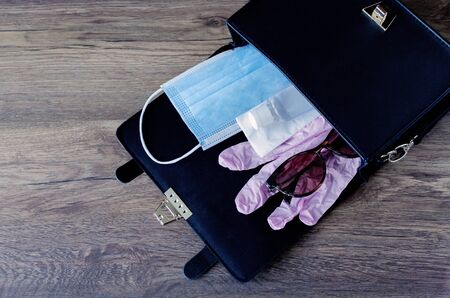 women's handbag with a medical mask, rubber gloves and a disinfector, close-up protection against COVID-19の写真素材