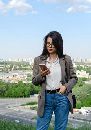 beautiful girl in a business suit with a phone in his hands, on the background of the city, close-up