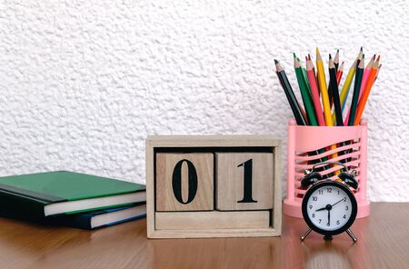 wooden calendar with date, alarm clock, color pencils on the table, books, close upの写真素材