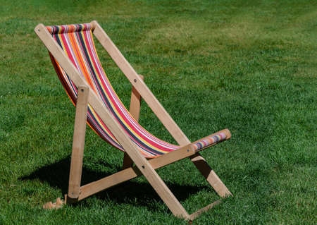 chaise longue stands on green grass, summer day, close up