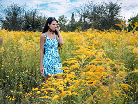 young girl in a straw hat surrounded by blooming yellow herbs, close upの写真素材