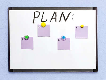 white board with a white board with a plan and colored sheets of paper for notes, on a light wall,...