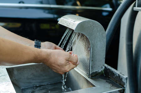 man washes his hands in a washbasin at a self-service car washの写真素材