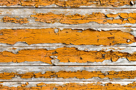 old wood plank with peeled orange paint, rough and weathered wood surfaceの写真素材