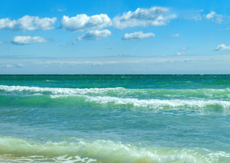 Picturesque landscape with sea waves and blue sky with white clouds. Natural background with copy space.の写真素材