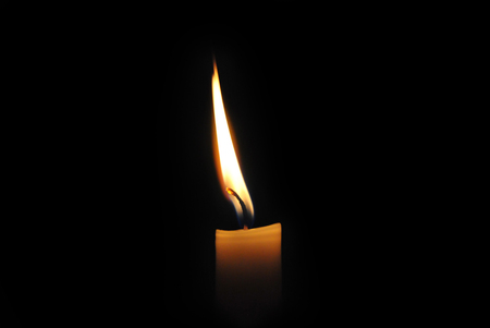 Close-up of a burning candle on a black background.の写真素材