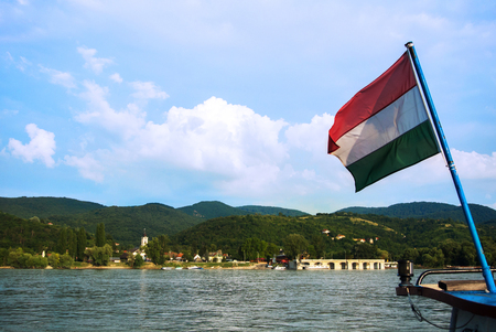 A view to a church at Visegrad, a small town at Hungary near Budapest from a ship at Danube, and a hungarian flag at the foreground.の写真素材