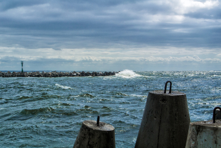 An embankment of Baltic sea at the city Baltiysk on cloudy summer day, a view to a mole, waves and big stone blocks at pier, the most western point of Russia, Kaliningrad region.の写真素材
