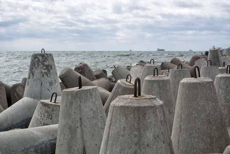 An embankment of Baltic sea at the city Baltiysk on cloudy summer day, a view to the gray seascape, waves and big stone blocks at pier, the most western point of Russia, Kaliningrad region.の写真素材