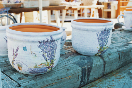 TIHANY, HUNGARY - AUGUST 05, 2017: Bright white textured hand-made pots with hand-painted bouquets of lavender and butterflies on a wooden table in the courtyard of a pottery workshop.のeditorial素材