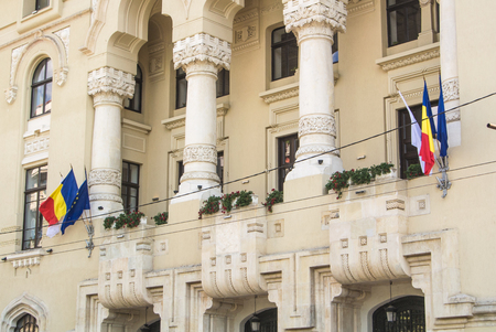 BUCHAREST, ROMANIA - JULY 29, 2017: Archetecture, state flags and trees in the central street of Bucharest, close-up of old beautiful buildings in the sun light, columns and windows.のeditorial素材