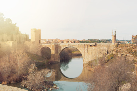An arch Alcantara Bridge over the Tagus River and its reflection in water on winter evening day, Toledo.の写真素材