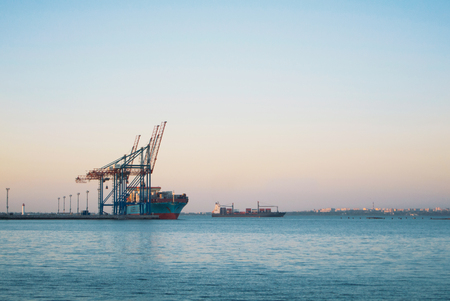 ODESSA, UKRAINE - OCTOBER 16, 2017: A big cargo ship and cargo cranes in Sea Marine Trade Port of Odessa in the evening with Black sea water on the background.のeditorial素材