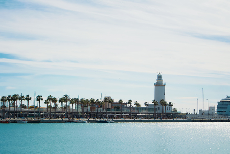 MALAGA, SPAIN - FEBRUARY 7, 2017: A landscape with La Farola lighthouse and a long beautiful promenade with palms, shops and yachts in the water.のeditorial素材