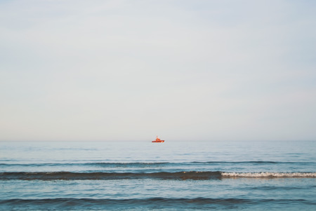 A view to Mediterranean sea and a red ship from a beach of Valencia in the evening, Spain.の写真素材