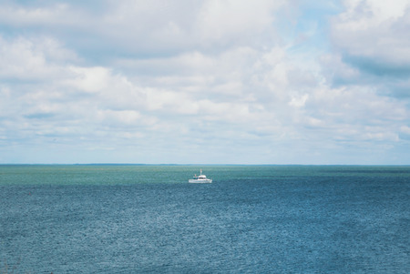A view to Baltic sea and a little white ship from a dune of Nida in the evening, Lithuania.