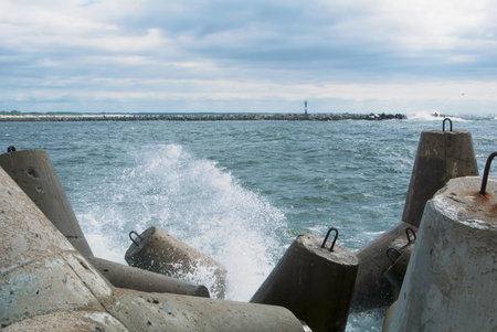 An embankment of Baltic sea at the city Baltiysk on cloudy summer day, a view to the gray seascape, waves and big stone blocks at pier, the most western point of Russia, Kaliningrad region.の写真素材