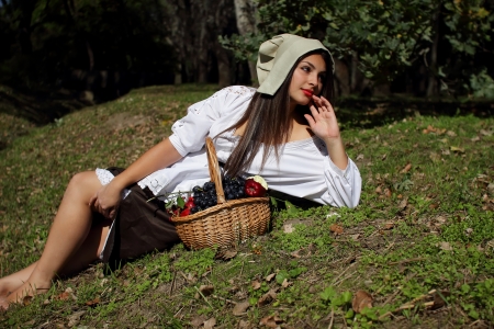 Beautiful girl in a white blouse, a hat resting on the lawnの写真素材