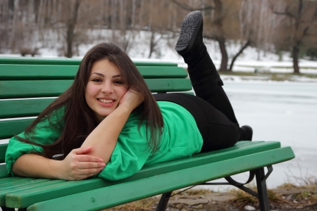 Beautiful girl lying on a bench and smilingの写真素材