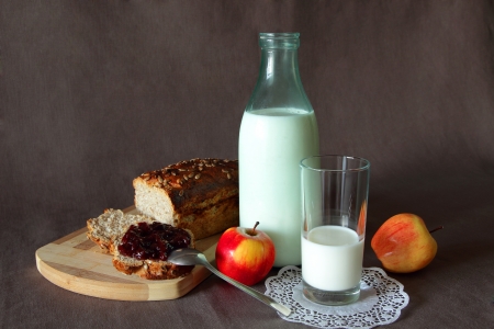 Healthy breakfast with fresh bread, smeared jam, a glass of milk and applesの写真素材
