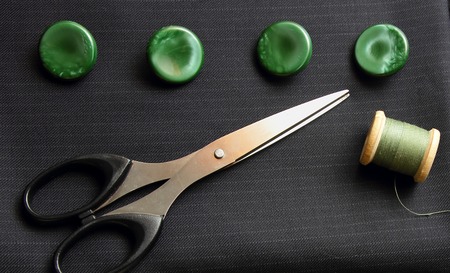 Black suiting fabric, scissors and green buttonsの写真素材