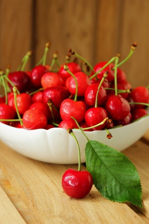 Ripe cherries in a bowl and one berry near herの写真素材
