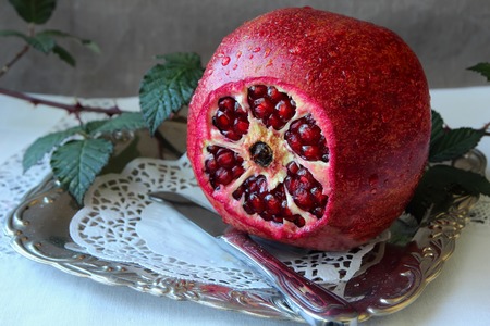 Ripe pomegranate with sliced ??tip on a platterの写真素材