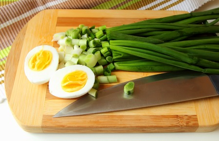 Egg, cut in half, and green onion on the boardの写真素材