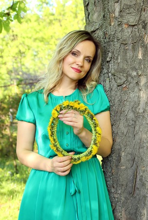 Beautiful girl with a wreath of dandelions in the hands ofの写真素材