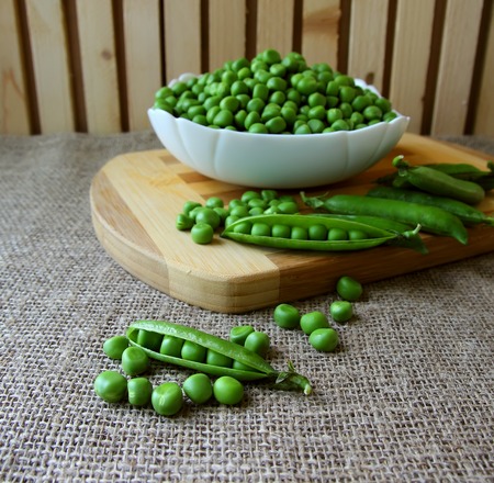 A pod of peas and a whole plate of peeled peas.の写真素材