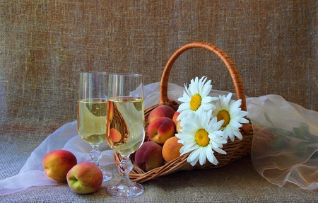 Two glasses of white wine, peaches and bunch of daisies.の写真素材