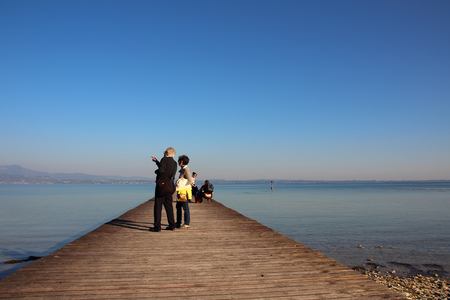 Elderly couple standing on the dock at Lake Garda in Sirmioneのeditorial素材