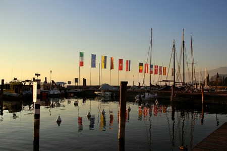 Bardolino, Italy, 2 November 2015,Coastline with flagpoles and boats at Lake Garda.のeditorial素材