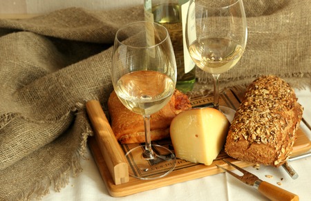 Two glasses with white wine, homemade bread and cheese.の写真素材