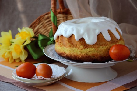 Easter cake, painted eggs and bouquet of daffodils.