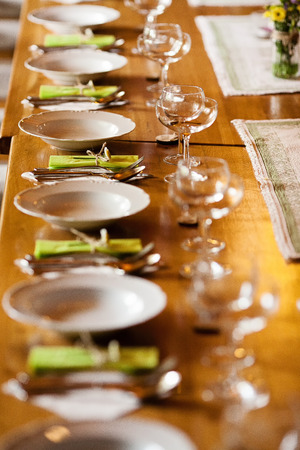 Rustic table setting ready for wedding dinner with white plates and green paper napkins