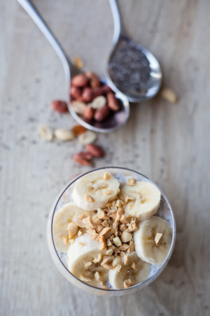 Banana chia yogurt pudding decorated with ripe sliced banana and peanutsの写真素材