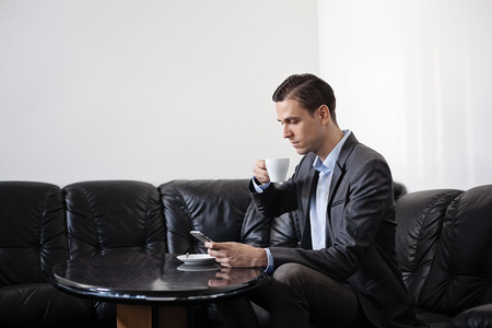 business man hands on a table with tablet, phone and cup of coffee in a officeの写真素材